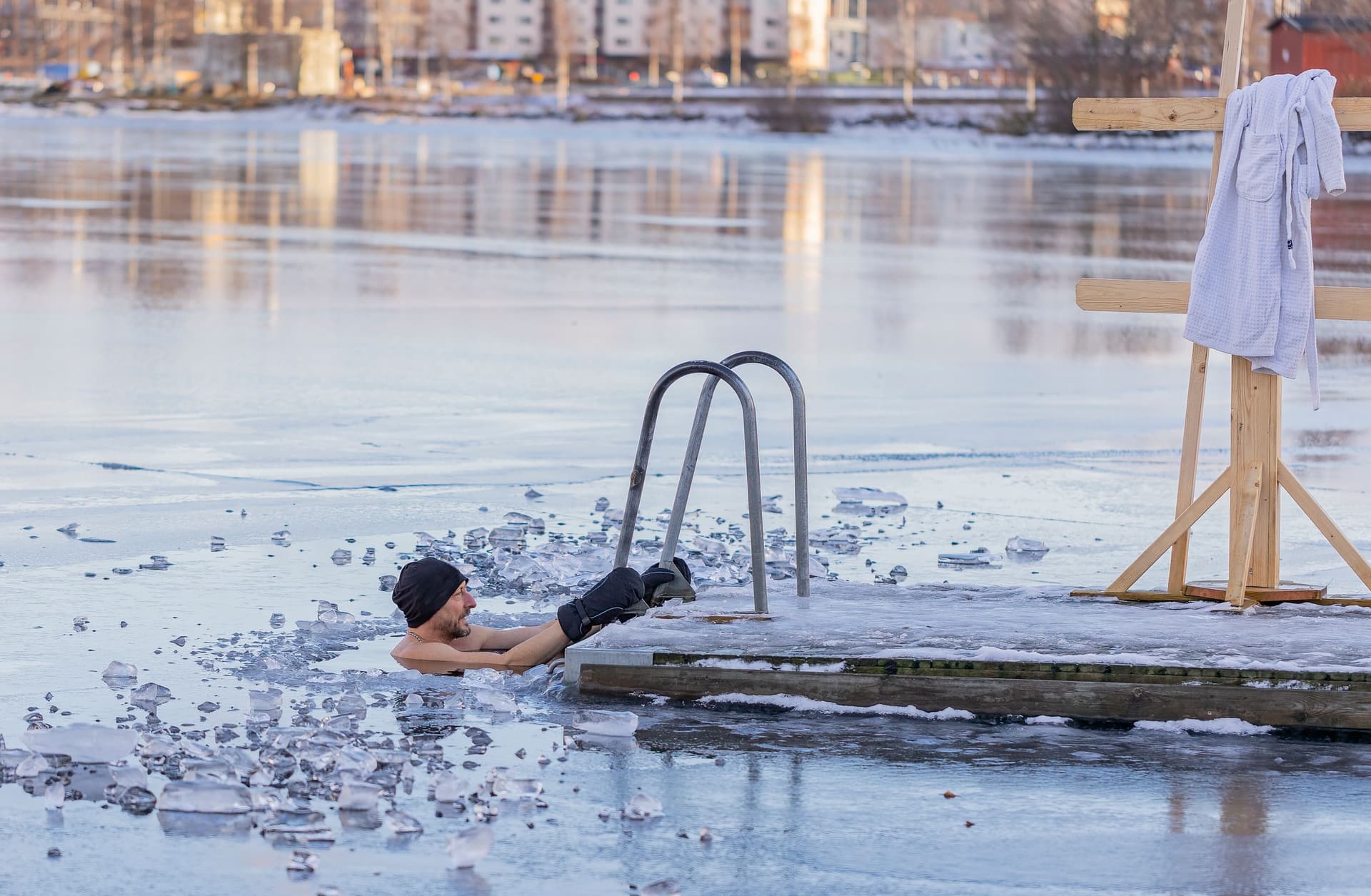 Mann som bader i isvann ved en brygge om vinteren