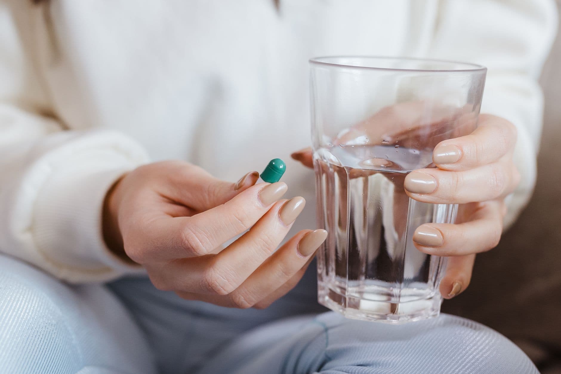 Kvinne holder en kollagenkapsel og et glass vann