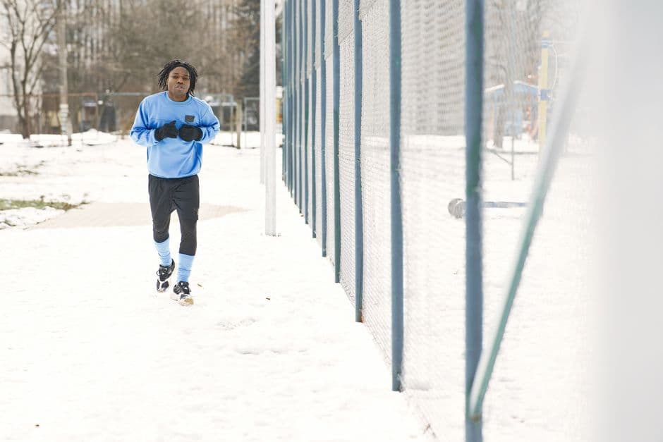 En mann jogger i kuldegrader på en snødekt sti om vinteren.
